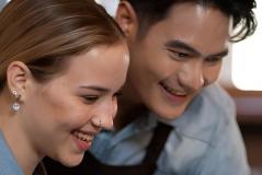 Close de um homem e uma mulher sorridentes, usando aventais, olhando para algo à frente.