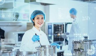 Imagem de uma cozinheira em uma cozinha industrial moderna, com utensílios de cozinha e tecnologia visível.