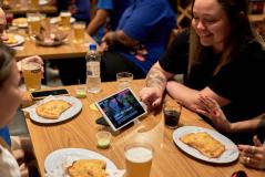 Clientes em bar com tablets de autoatendimento da Goomer durante evento de alta demanda no foodservice