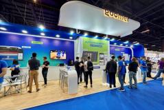 Visitantes na feira de tecnologia interagindo com sistemas de autoatendimento no espaço de autoatendimento de um evento de tecnologia, destacando inovação e atendimento ao cliente.