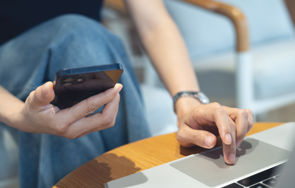 Pessoa usando celular e laptop ao mesmo tempo, representando o uso da tecnologia para gestão inteligente de negócios.
