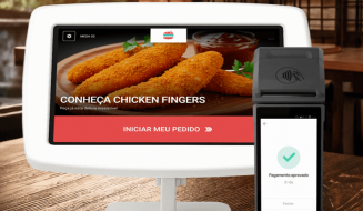 Tela de um sistema de pedidos de comida digital exibindo opções para solicitar pratos, incluindo nuggets de frango, com pagamento aprovado na tela portátil ao lado.