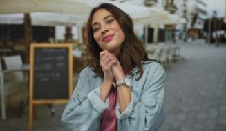 Mulher sorridente na rua, vestida casualmente, demonstrando felicidade e autoestima, com cenário urbano ao fundo, perfeito para ilustrar autoestima e bem-estar.