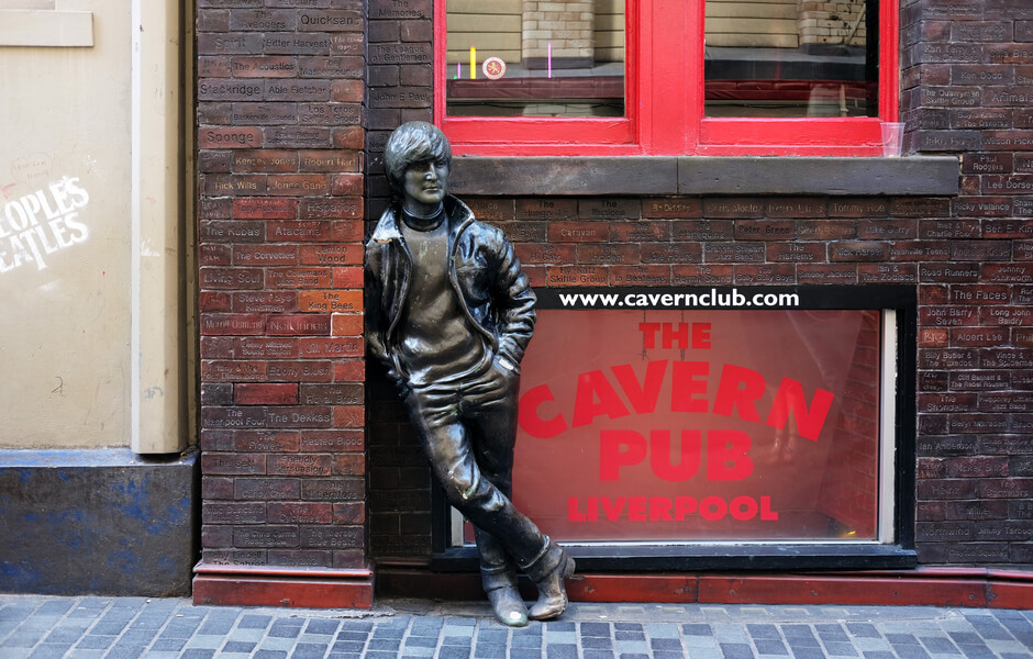 Imagem da fachada do "cavern club" em Liverpool. Nela, há uma estátua do John Lennon.