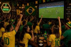 Interior de um restaurante ou bar decorado para a Copa do Mundo, cheio de clientes com camisas do Brasil comemorando e assistindo ao jogo de futebol em um grande telão.