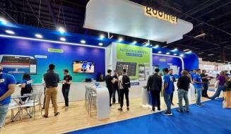 Visitantes na feira de tecnologia interagindo com sistemas de autoatendimento no espaço de autoatendimento de um evento de tecnologia, destacando inovação e atendimento ao cliente.