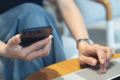 Pessoa usando celular e laptop ao mesmo tempo, representando o uso da tecnologia para gestão inteligente de negócios.