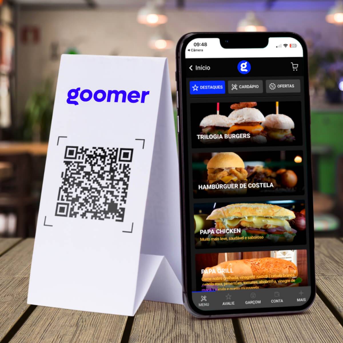 Smartphone ao lado de um card com o QR Code do Cardápio Digital Goomer 