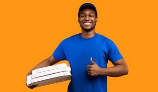Entregador de pizza sorridente com uniforme azul, segurando caixas de pizza, em fundo laranja, promovendo serviço de delivery de pizza.
