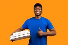 Entregador de pizza sorridente com uniforme azul, segurando caixas de pizza, em fundo laranja, promovendo serviço de delivery de pizza.