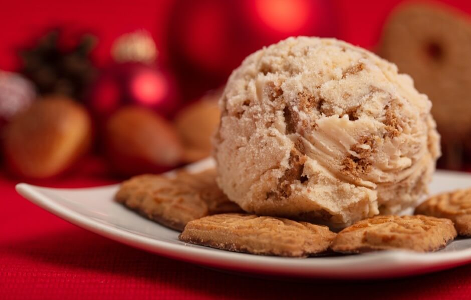 Deliciosa bola de sorvete acompanhada de biscoitos em um prato, com fundo decorativo natalino, ideal para as festividades de fim de ano.