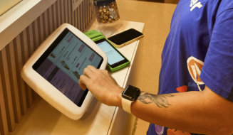 Pessoa utilizando um totem em um ambiente de restaurante, interagindo com um sistema digital de pedidos.