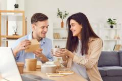 Homem feliz recebendo presente de uma mulher, momento de confraternização e amizade em ambiente de sala de estar moderna com decoração minimalista.
