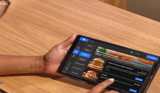 Pessoa usando um tablet para fazer pedidos de hambúrgueres gourmet em um aplicativo de delivery.