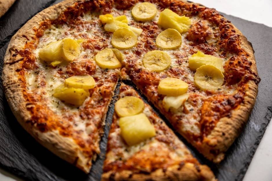 Pizza de banana com curry em um recipiente de cerâmica escura com uma fita destacada