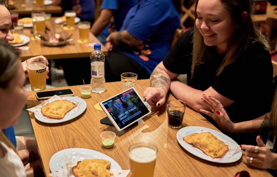 Clientes em bar com tablets de autoatendimento da Goomer durante evento de alta demanda no foodservice