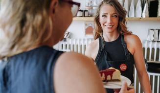 Mulher e jovem garçon usando um laptop em um restaurante, conversando sobre o cardápio ou uma solicitação, ambiente sofisticado e elegante