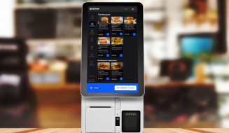 Menino usando uma máquina de pedidos de comida digital em um restaurante, com a tela exibindo várias opções de hambúrgueres e refeições para fazer pedidos online.