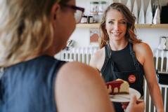 Mulher e jovem garçon usando um laptop em um restaurante, conversando sobre o cardápio ou uma solicitação, ambiente sofisticado e elegante