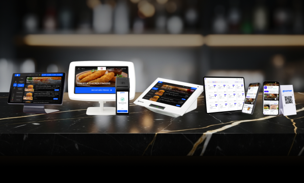 Diversos dispositivos digitais exibindo plataformas de pedidos online de alimentos, incluindo tablets, smartphones e computadores, enquanto estão dispostos em uma mesa de mármore escura em um ambiente moderno.
