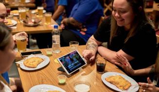 Clientes em bar com tablets de autoatendimento da Goomer durante evento de alta demanda no foodservice
